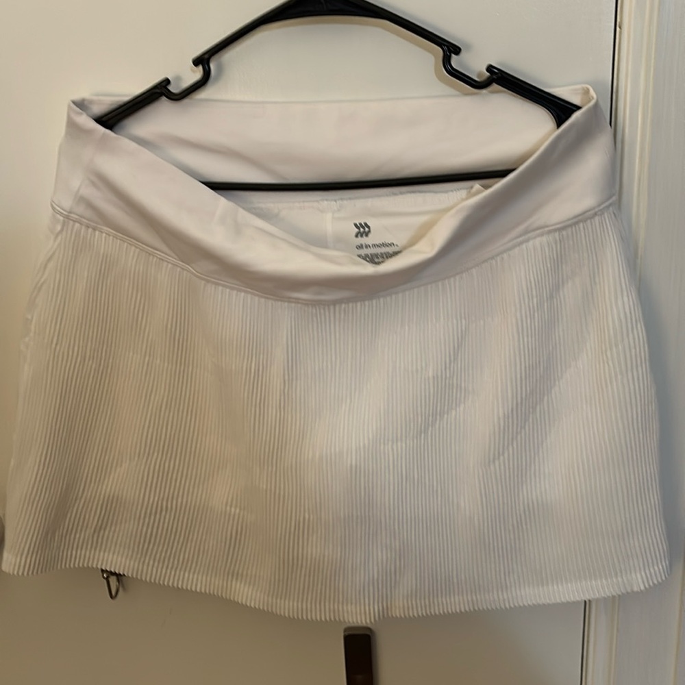 White tennis skirt with pleats and side pockets inside.